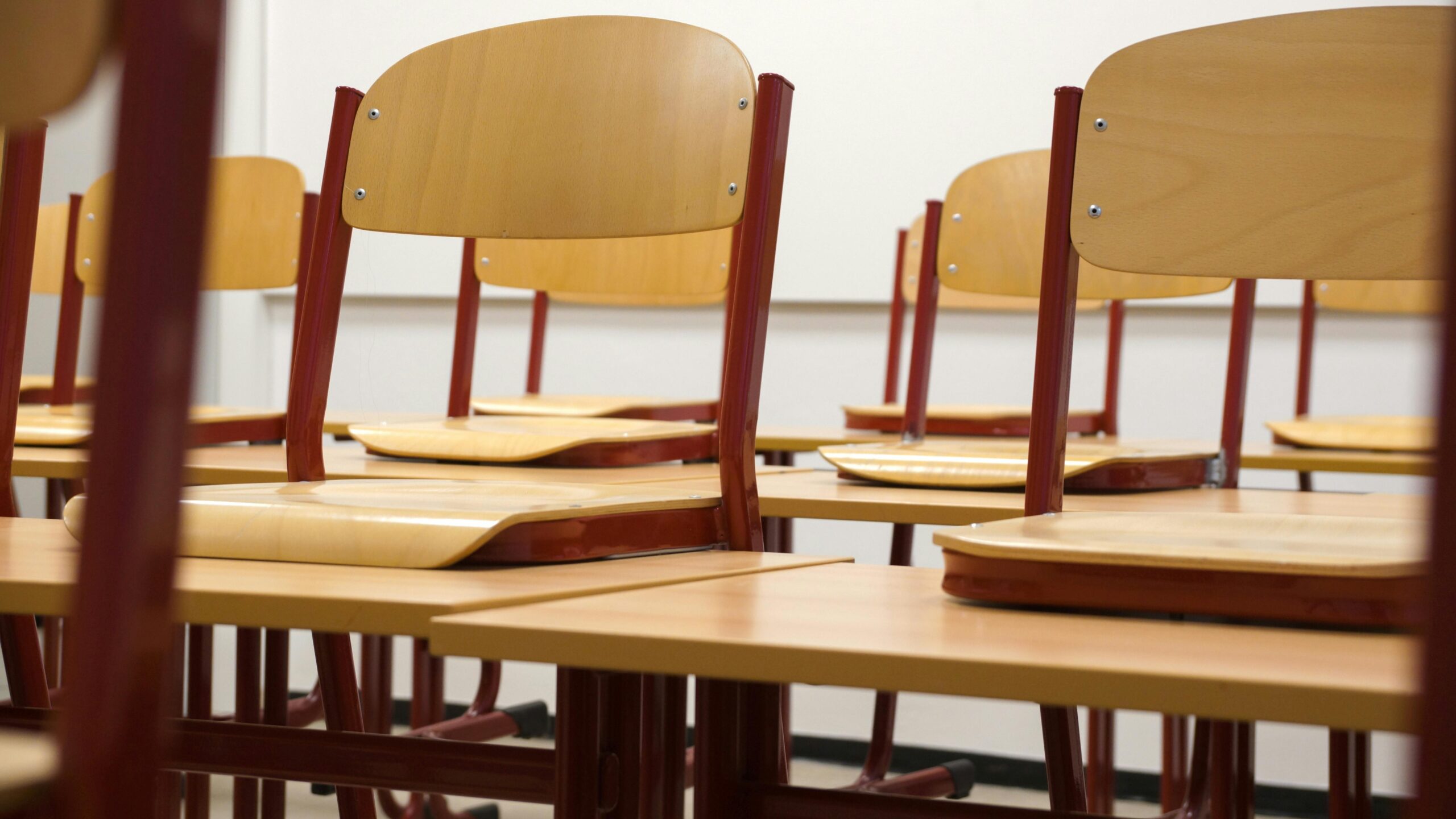 A modern and empty classroom featuring wooden chairs and desks with a focus on education and learning spaces.