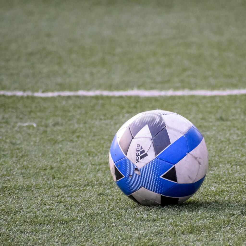 Close-up of a black and blue soccer ball resting on a green field, perfect for sports themes.